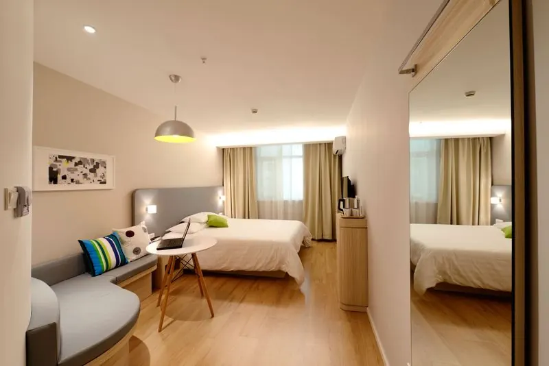 Spacious clean modern hotel room with neutral tones, a made bed and soft natural light